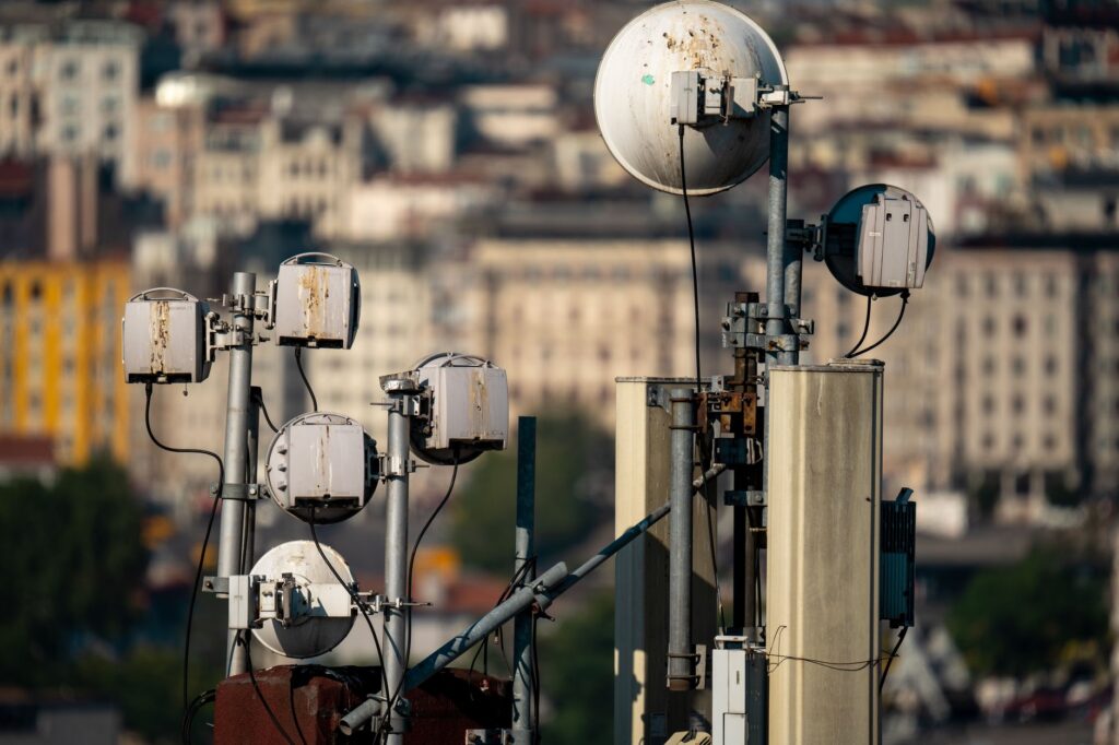 Rooftop cellular and microwave antennas on steel poles above a hillside of city buildings