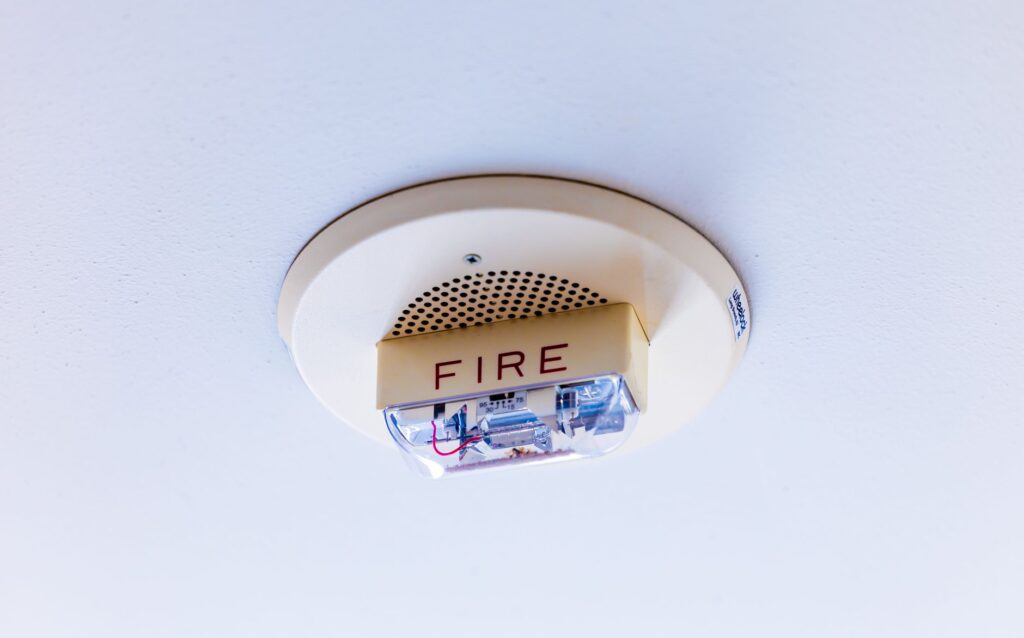 A ceiling-mounted fire alarm horn and strobe, its amber plate lettered FIRE