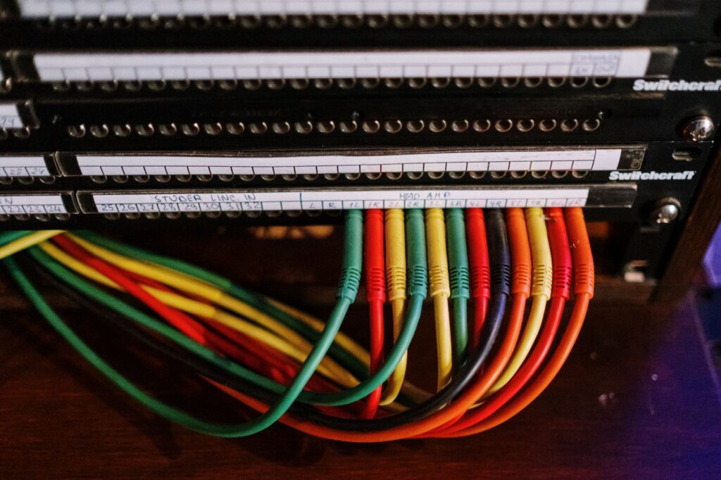 Red, green and yellow patch cords plugged into a labelled rack-mounted patch panel