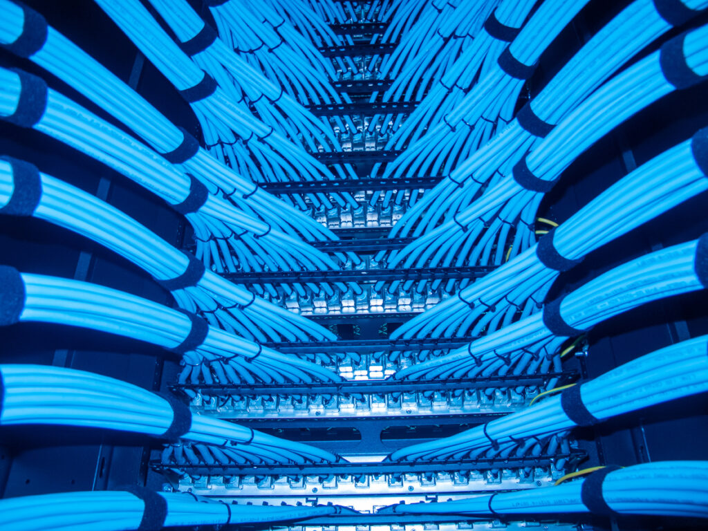 Bundles of blue network cables neatly dressed along both sides of a cable tray
